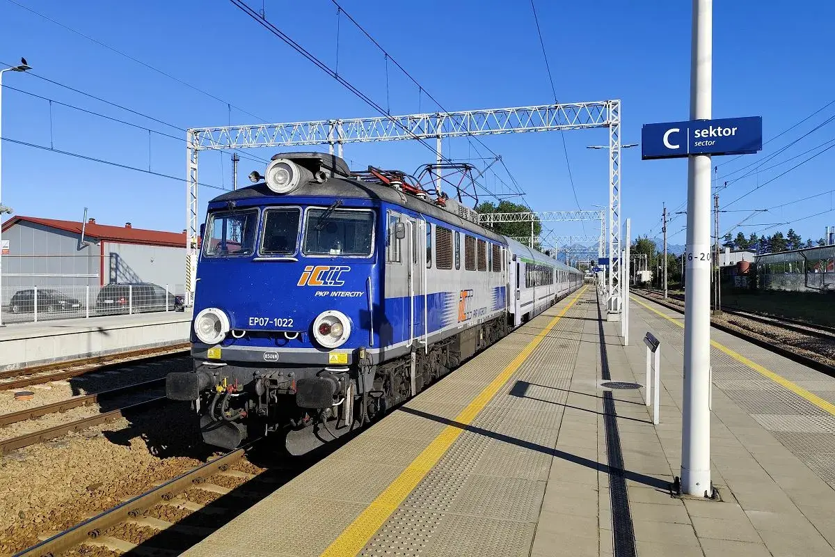 Niebiesko-szary pociąg PKP Intercity EP07-1022 stoi na peronie. Zastanawiasz się, ile jedzie pociąg z Poznania do Krakowa?