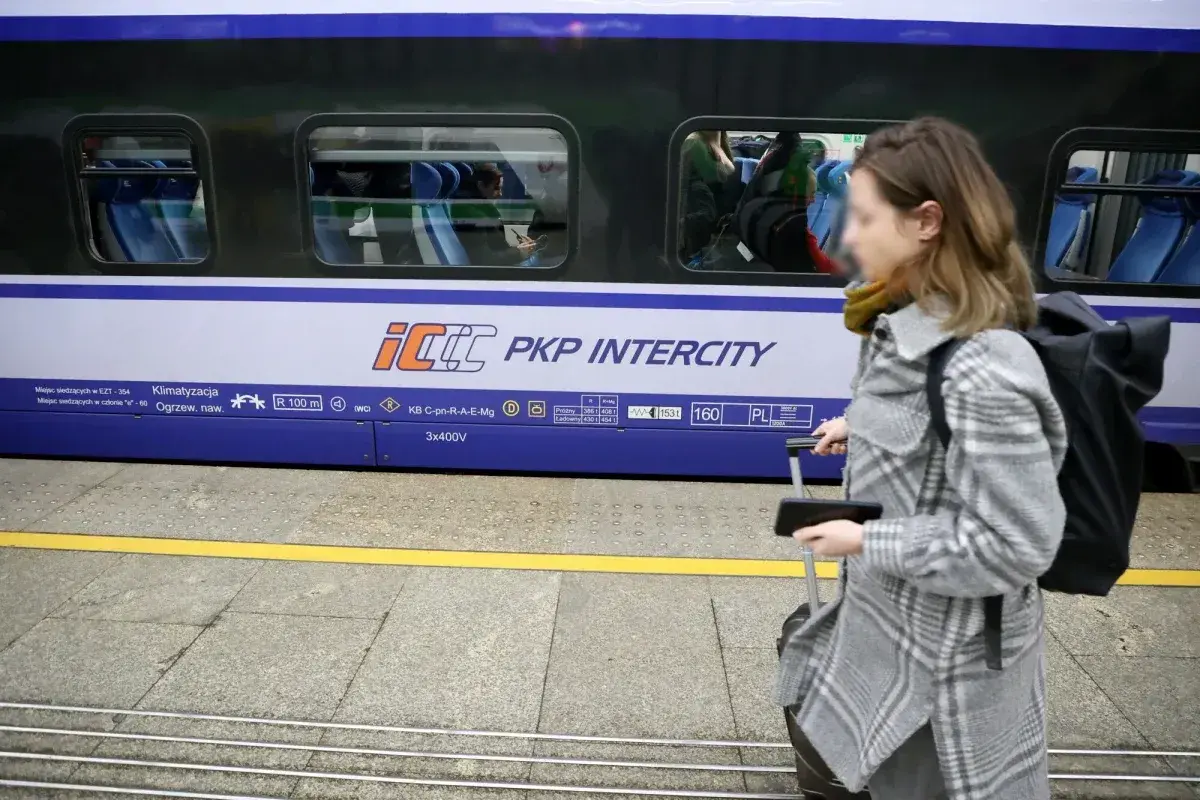 Kobieta z walizką na peronie PKP Intercity, przygotowuje się do podróży mimo podwyżek cen biletów.