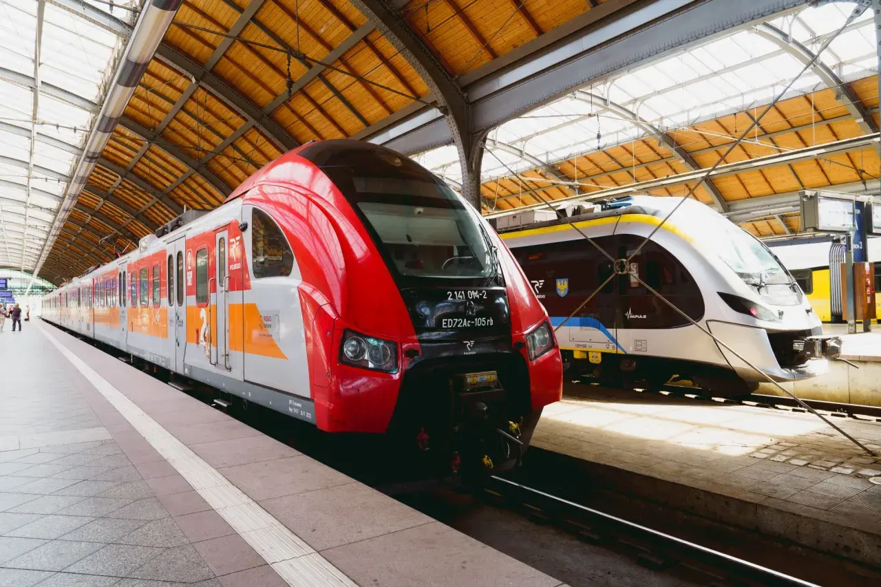 Dwa nowoczesne pociągi stojące na peronie. Czerwony pociąg Polregio i biało-niebieski Impuls, gotowe do podróży. Połączenie kolejowe Wrocław.