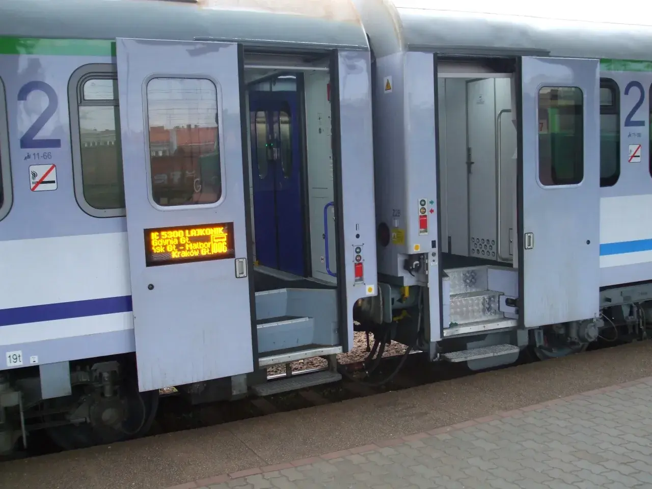 Drzwi wagonu TLK otwarte, widoczne schodki i tablica informacyjna. Jak otworzyć drzwi w TLK? Zwykle przyciskiem lub klamką.
