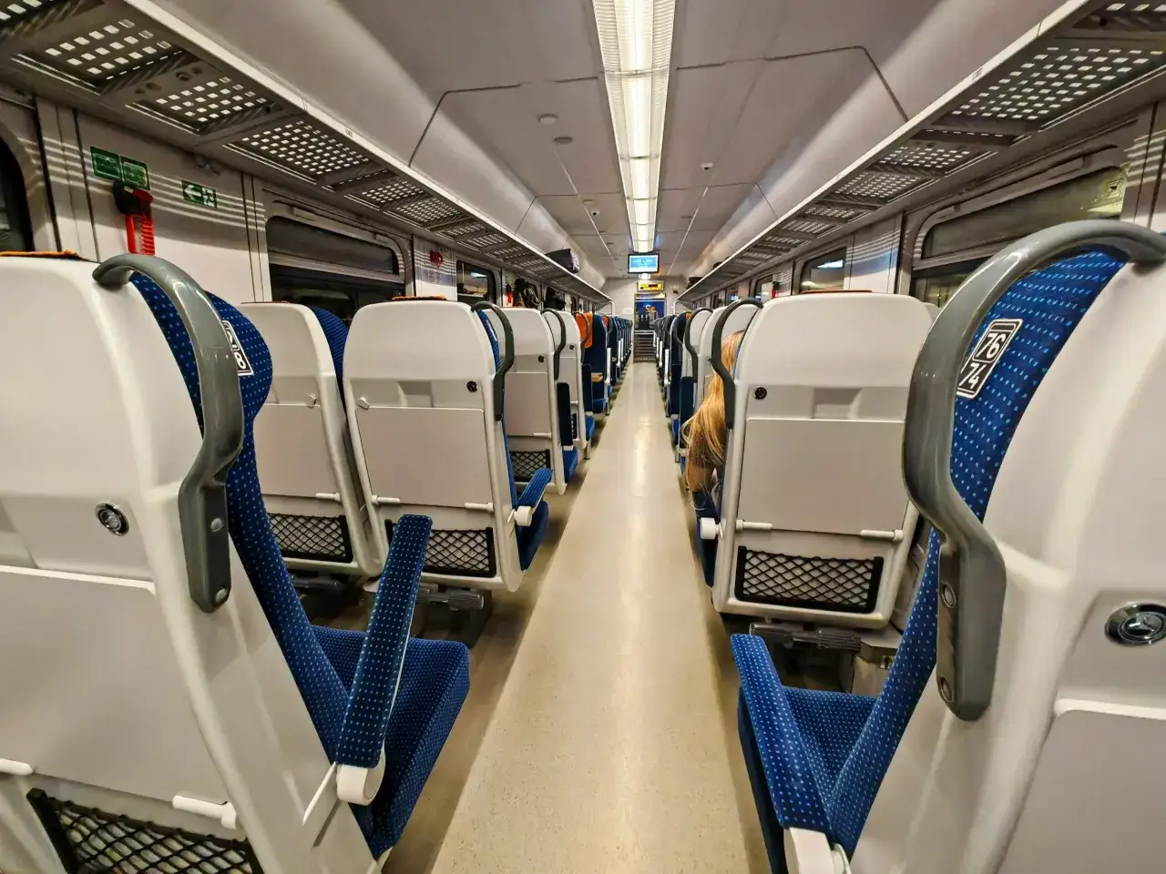 Wnętrze pociągu Pendolino z białymi siedzeniami i niebieskimi zagłówkami. Zastanawiasz się, ile kosztuje bilet na Pendolino?
