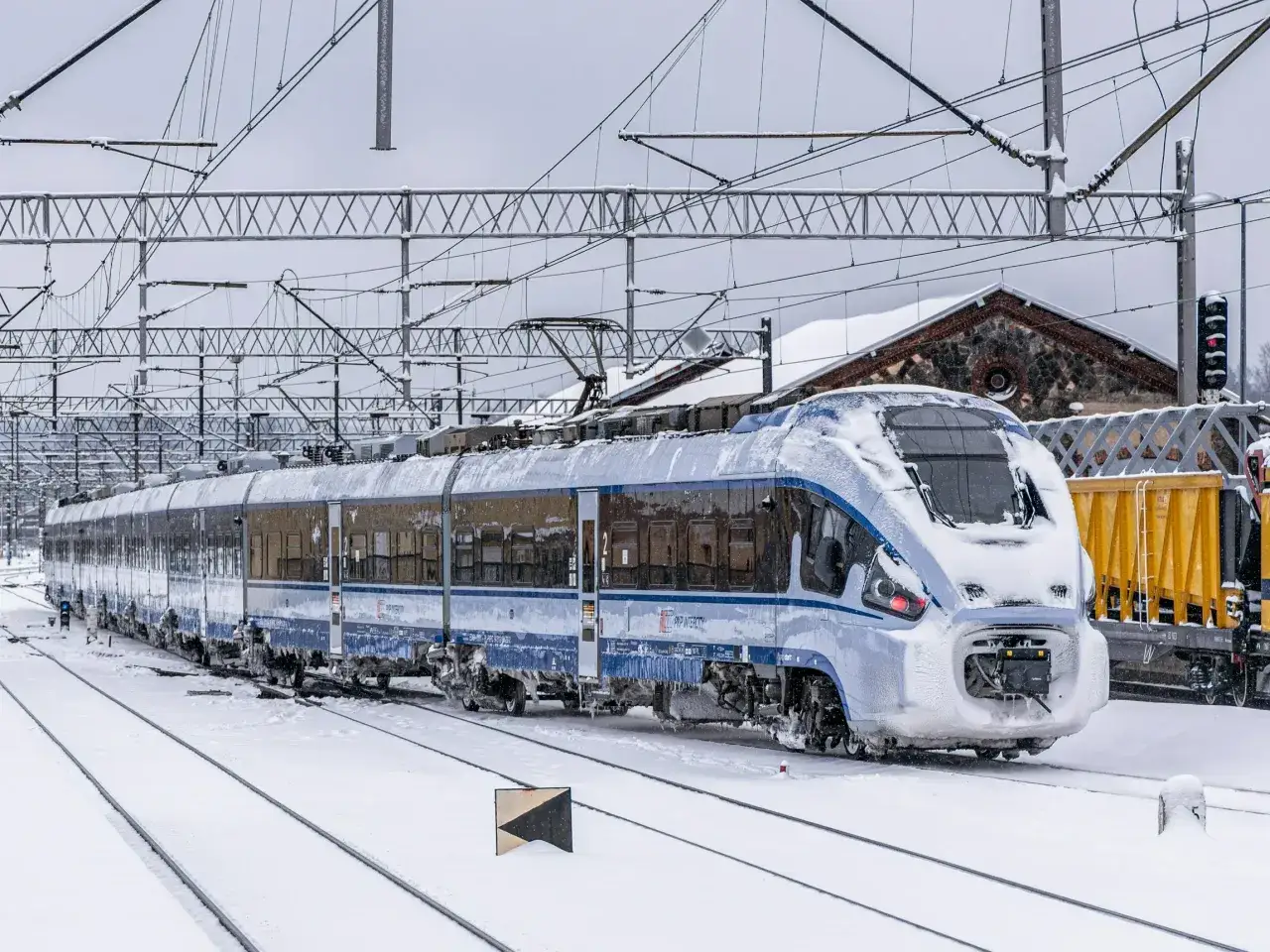 Zimowy dzień na torach. Pociąg PKP Intercity pokryty śniegiem i lodem, gotowy do podróży. Niskie temperatury nie straszne dla niskich cen, prawdziwi lowcy promo PKP!