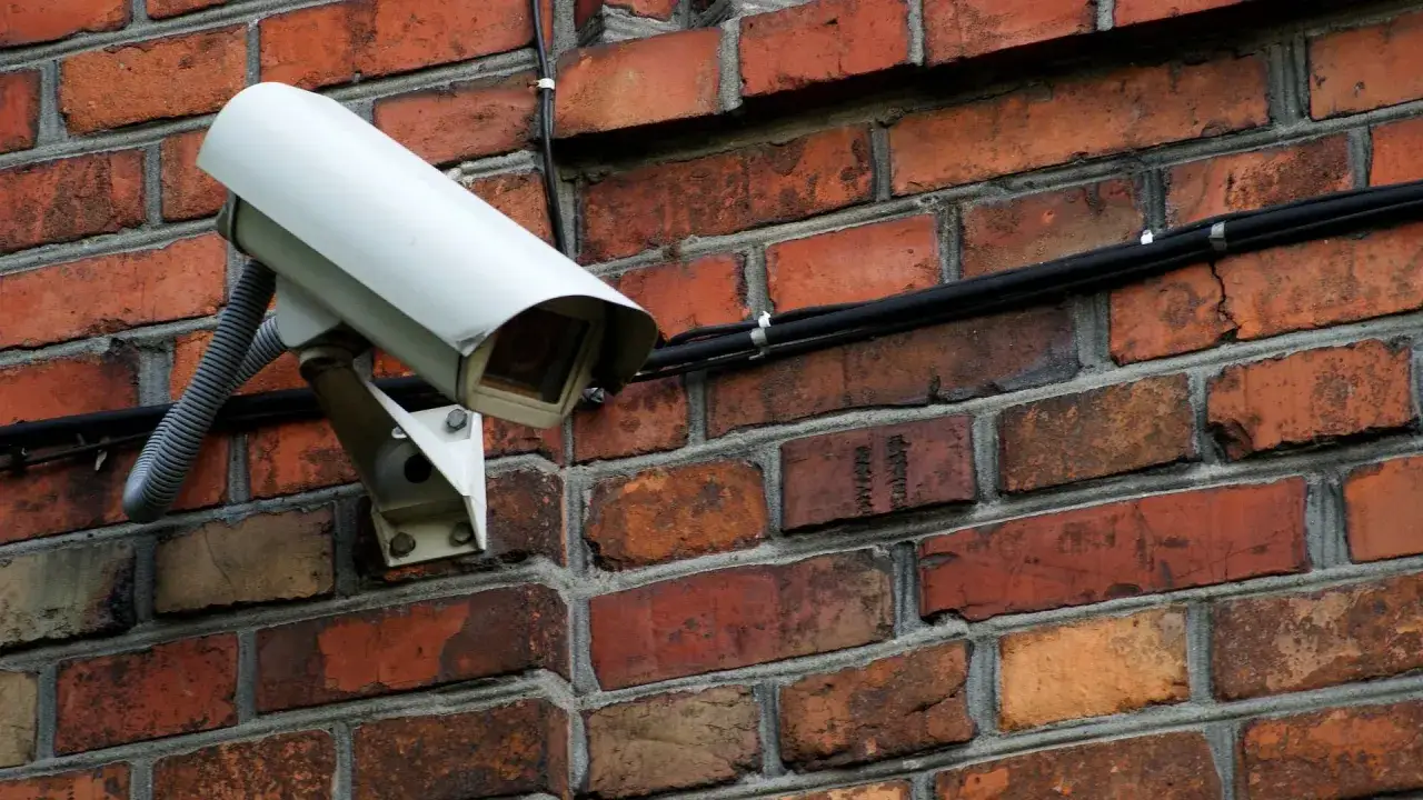 Kamery Słupsk dworzec czuwają nad bezpieczeństwem. Biała kamera monitoringu na ceglanej ścianie.