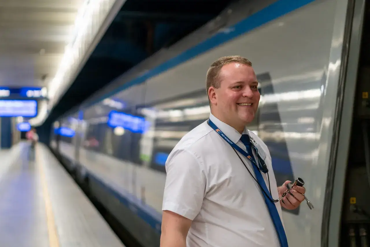 Uśmiechnięty pracownik PKP Intercity z kluczem w dłoni, gotowy do pracy. Czas na przerwa techniczna PKP.