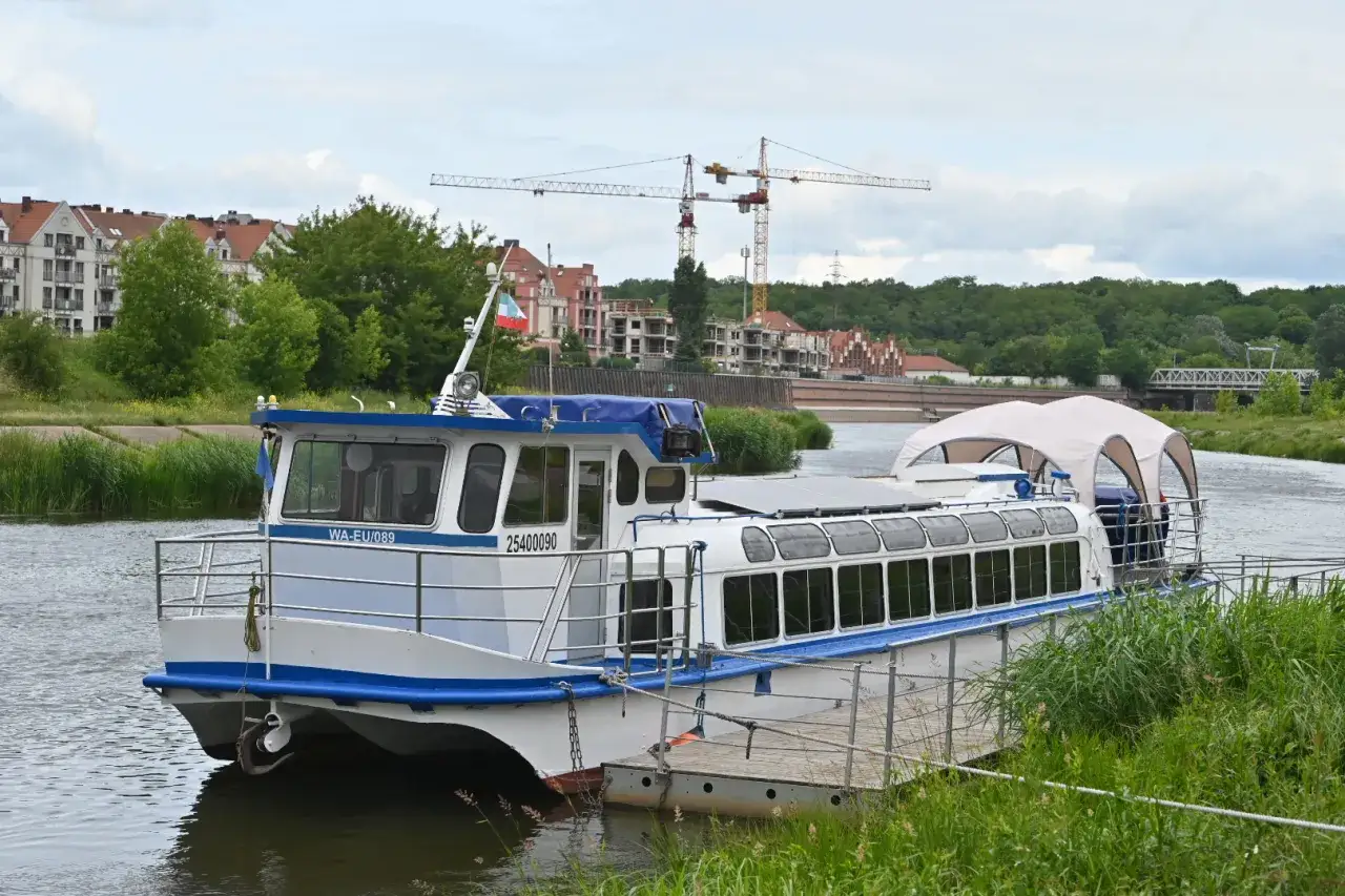 Statek pasażerski przycumowany do brzegu Warty w Poznaniu, gotowy na rejsy.