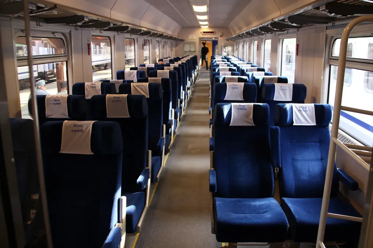 Wnętrze wagonów intercity bez przedziałów. Puste, niebieskie siedzenia czekają na pasażerów.