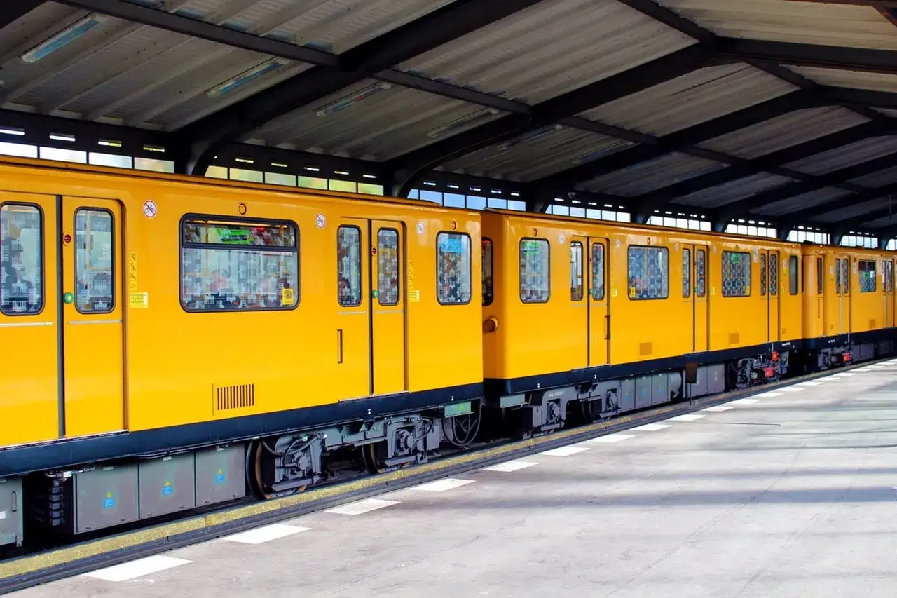 Żółty pociąg berlińskiej S-Bahn stoi na peronie pod zadaszeniem.