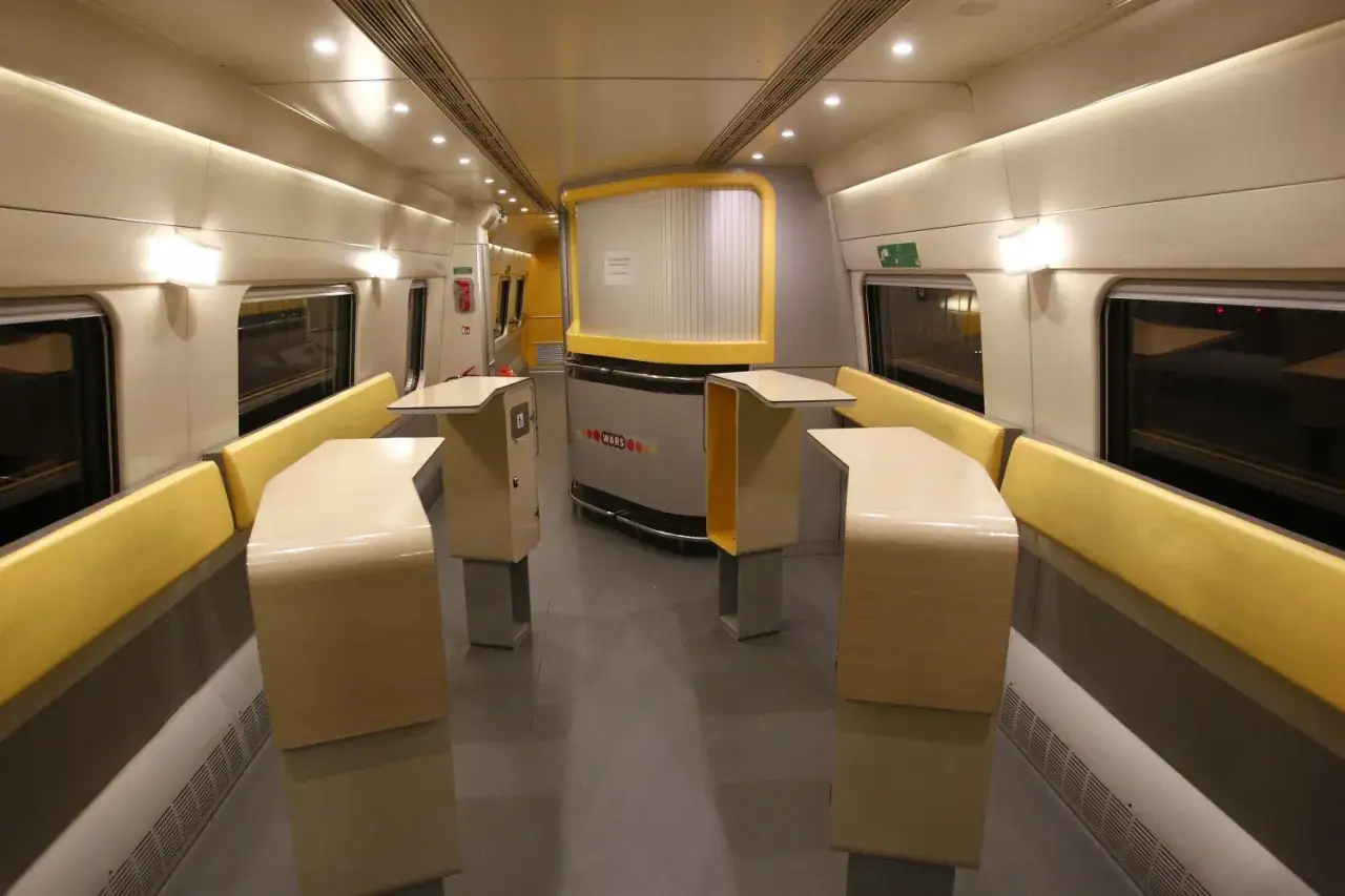 Wnętrze wagonu Pendolino, idealne na podróż Kraków Warszawa. Jasne siedzenia i stoliki tworzą komfortową przestrzeń.