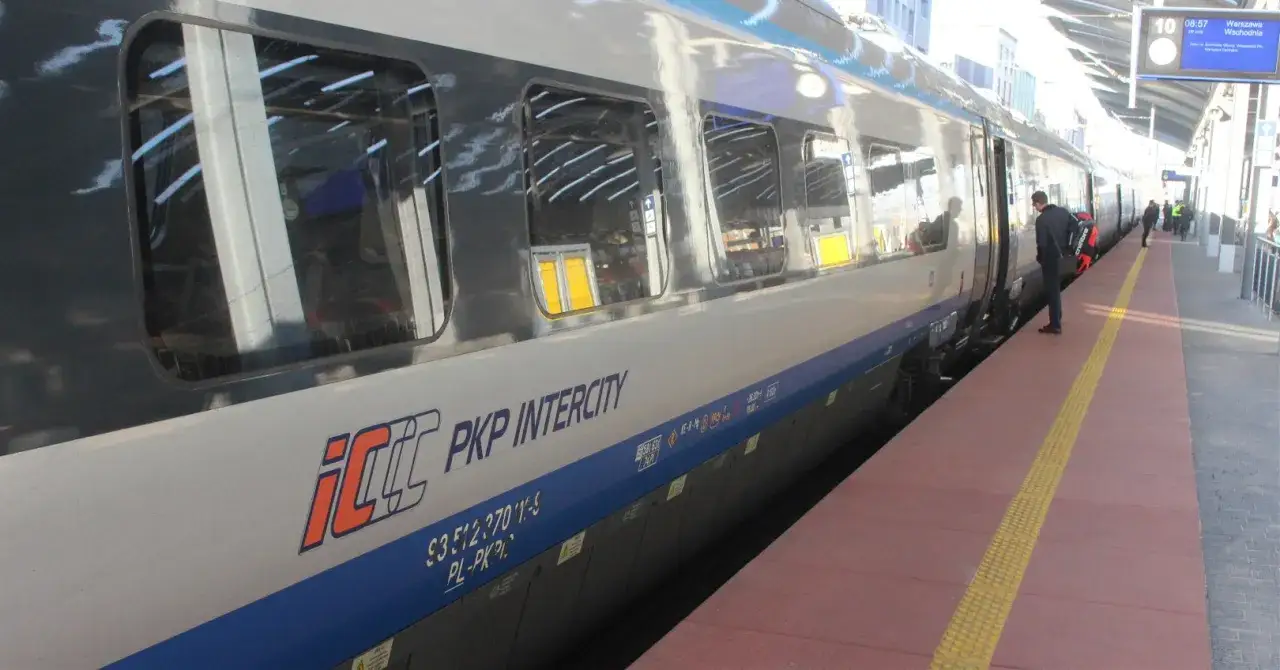 Pociąg do Giżycka PKP Intercity stoi na peronie. Mężczyzna z torbą czeka na wejście.
