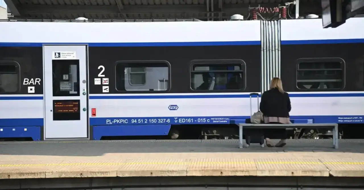 Kobieta z walizką czeka na pociąg PKP. Łowcy promo PKP wypatrują okazji do podróży.