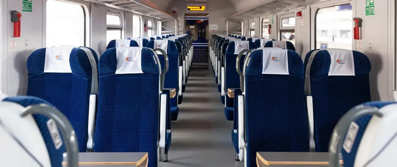 Puste, granatowe siedzenia w wagonie kolejowym PKP Intercity. To właśnie znaczy intercity – podróżowanie po Polsce w komforcie.