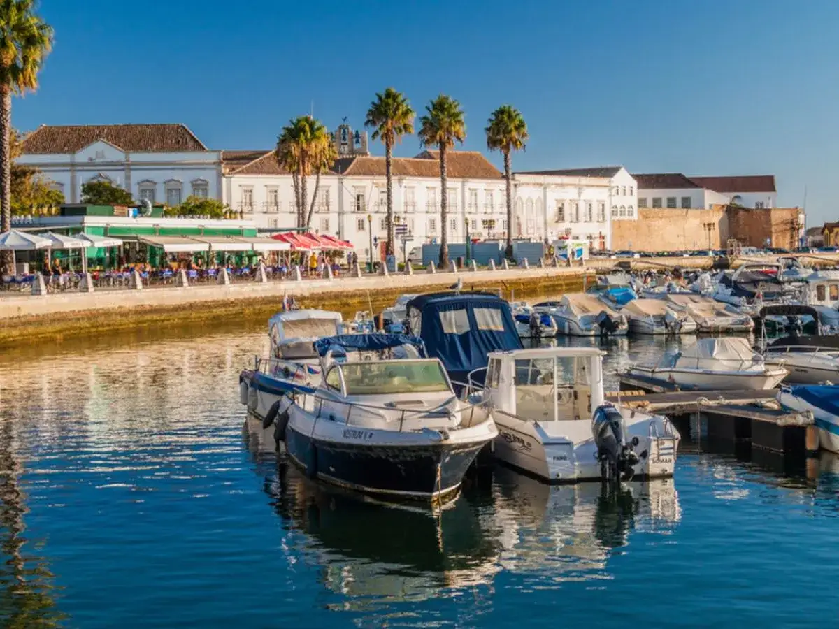 Port w Faro z łodziami i palmami. Warto zobaczyć w Faro to urokliwe nabrzeże z restauracjami i zabytkową architekturą.