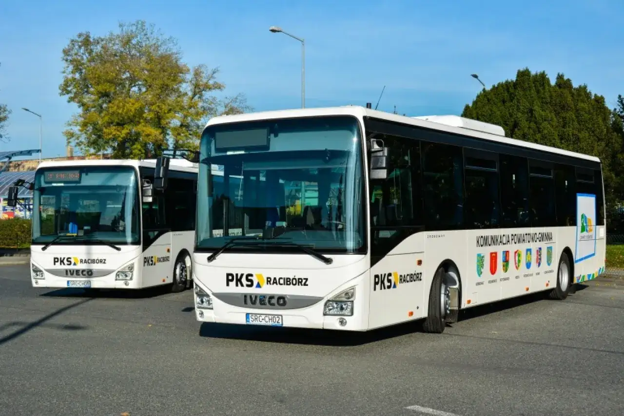 Dwa białe autobusy PKS Racibórz stoją na parkingu. Czekają na pasażerów, kiedy przyjedzie Racibórz.