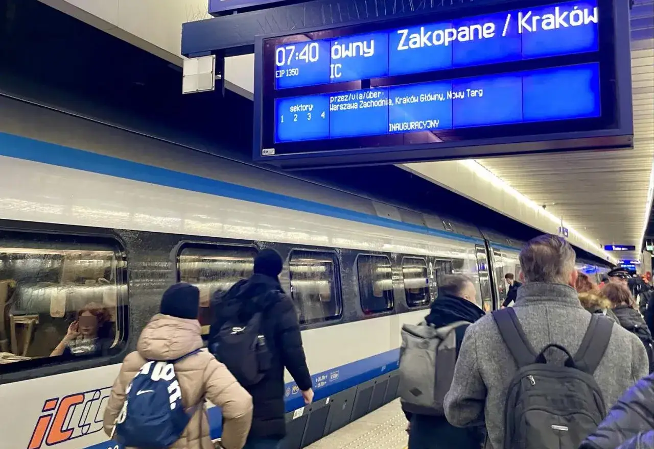 Pasażerowie czekają na pociąg Pendolino do Krakowa. Na tablicy informacyjnej widnieje komunikat o trasie do Zakopanego, przez Warszawę.