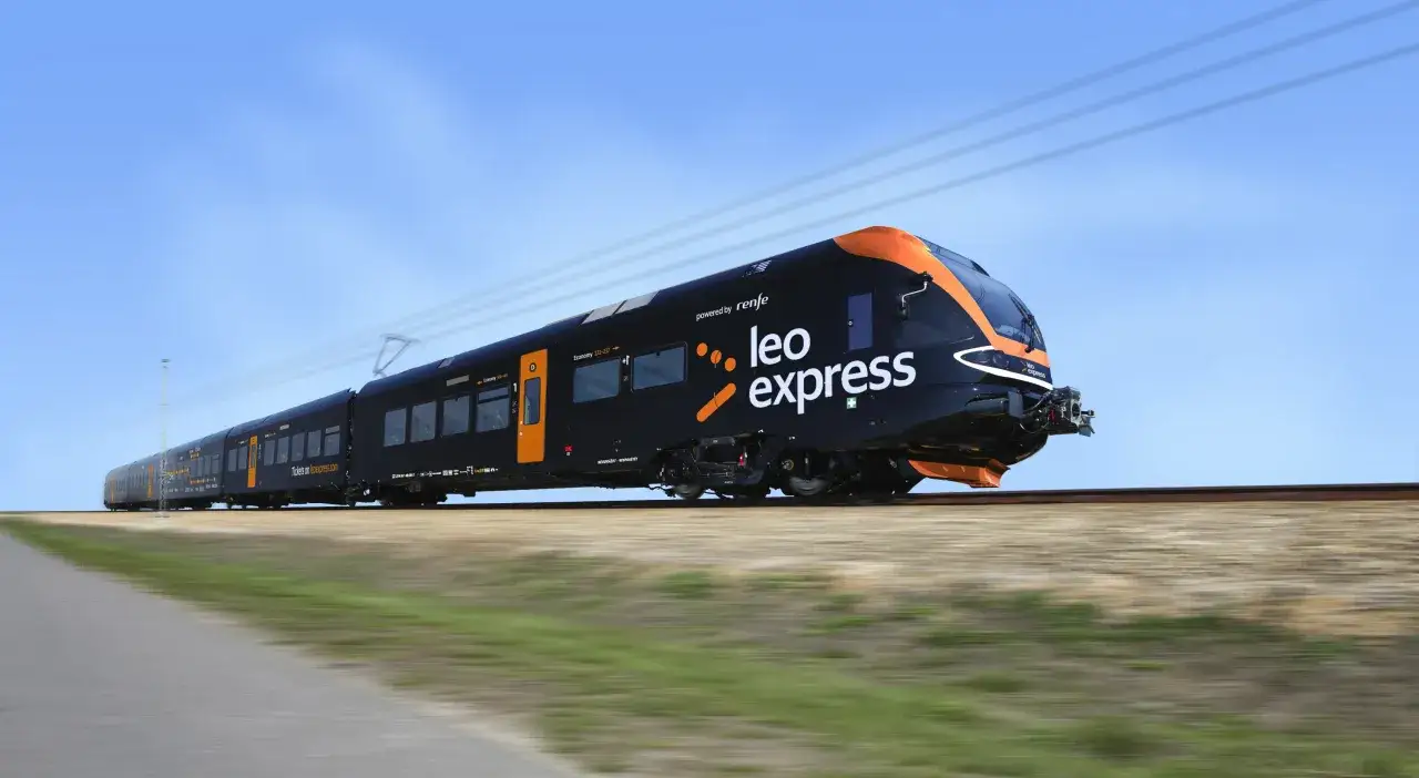 Czarny pociąg Leo Express z pomarańczowymi akcentami pędzi po torach. Szybki transport między Warszawą a Krakowem.