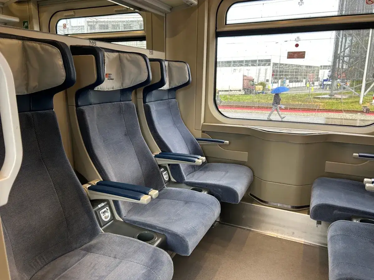 Wnętrze pociągu PKP Intercity z wygodnymi siedzeniami. Ile wagonów ma pociąg IC? Tego nie widać, ale podróż zapowiada się komfortowo.